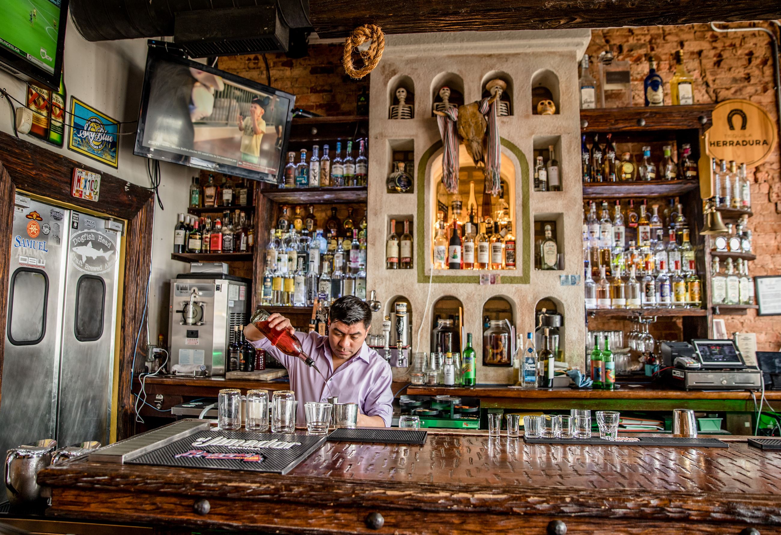 bartender mixes drinks behind bar in mexican restaurant