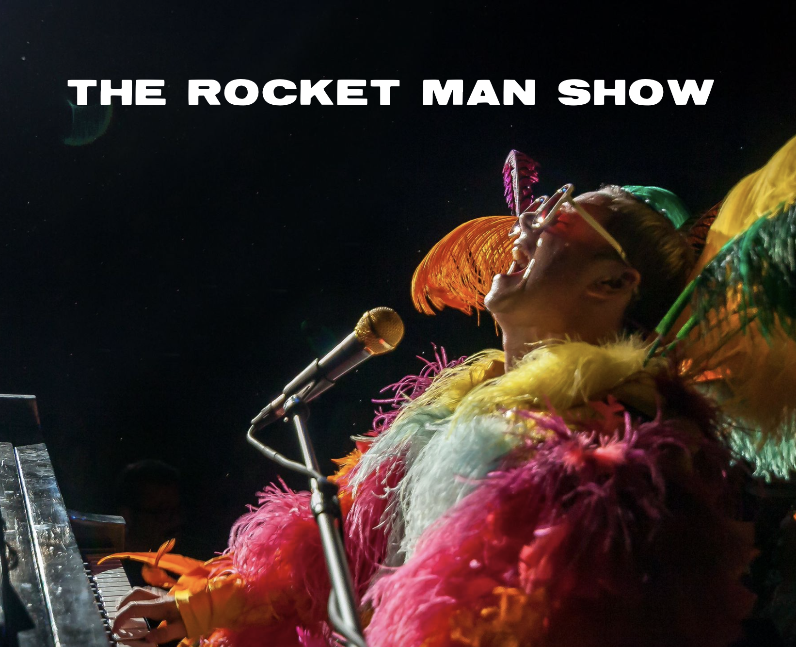 Singing loudly with head back, colorful costume, mic, piano, and black background with spotlight